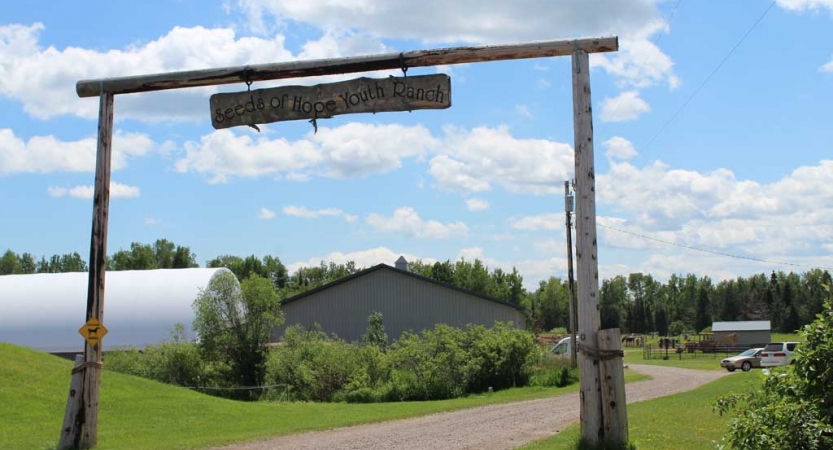 The entrance to an assumed ranch stands before some buildings in the background. 